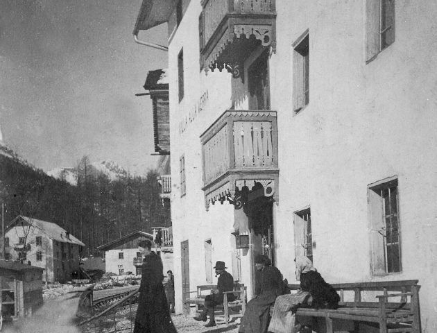 Foto storica di parte dell'Hotel Des Alpes, alcune persone sono sedute su delle panche